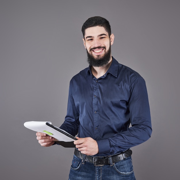 Concentrated young attractive businessman in blue shirt planning and writing in clipboard