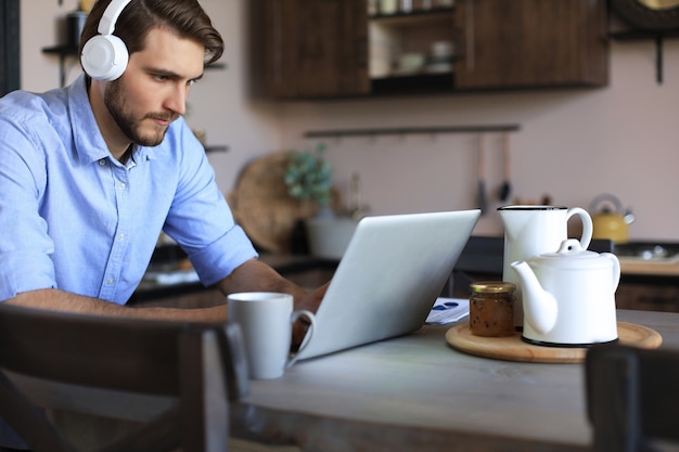 Concentrated young freelancer businessman using laptop for video conferance, working remotely online at home.