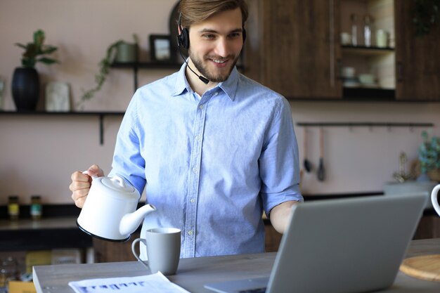 Concentrated young freelancer businessman using laptop for video conferance, working remotely online at home.