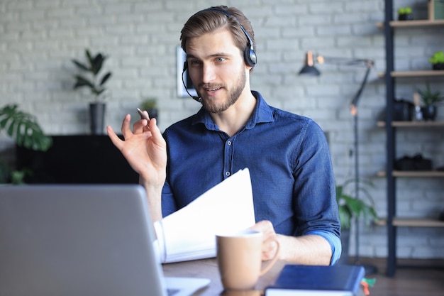 Concentrated young freelancer businessman using laptop for video conferance, working remotely online at home.