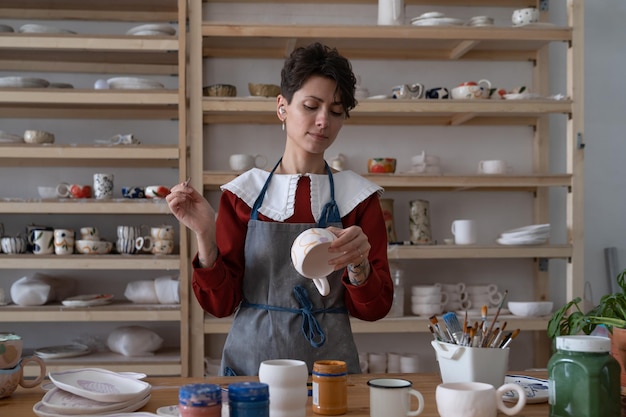 Concentrated young woman professional pottery artisan work in studio