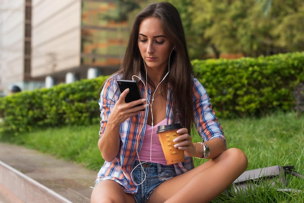 Concentrated young woman typing a text message on her mobile phone outdoors Serious female using smartphone