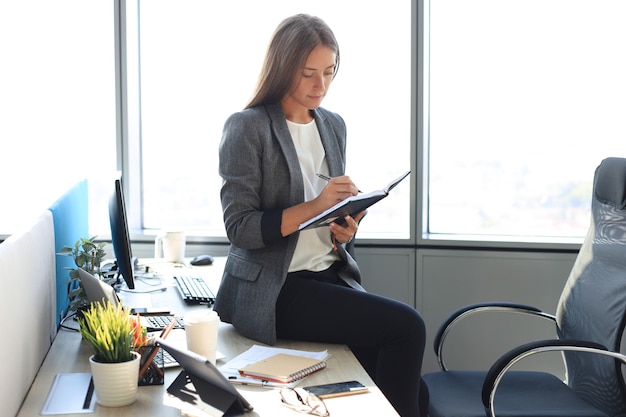 Concentrated young woman writing something down while working in the office.