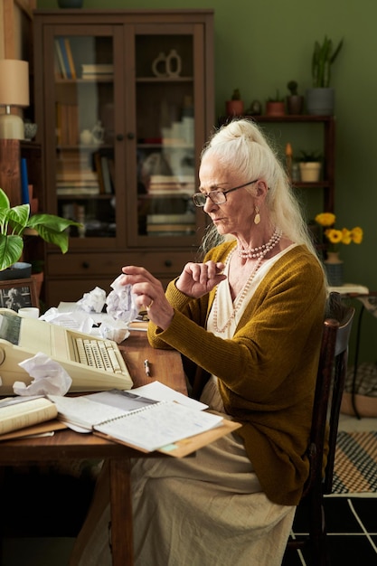 Concentrating Senior Woman Working on Typewriter in Office