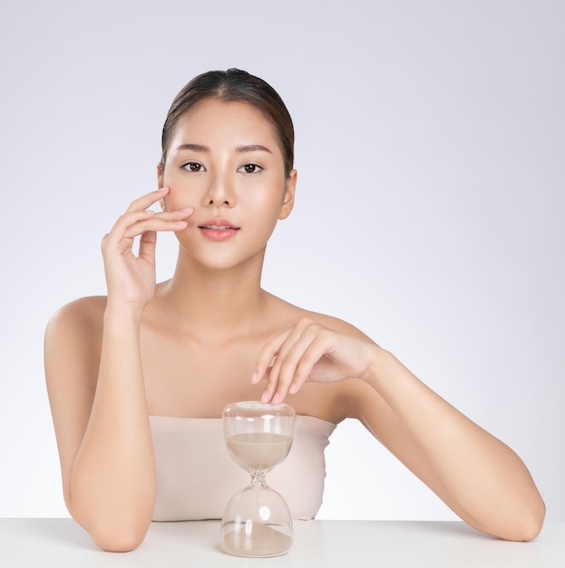 The concept of antiaging demonstrated by a portrait of a gorgeous young woman holding an hourglass Skincare treatment beauty care