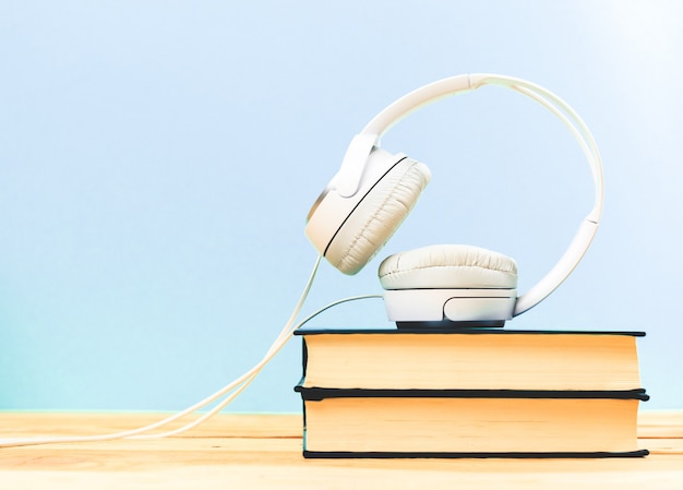 Concept of audiobook. Books on the table with headphones put on them