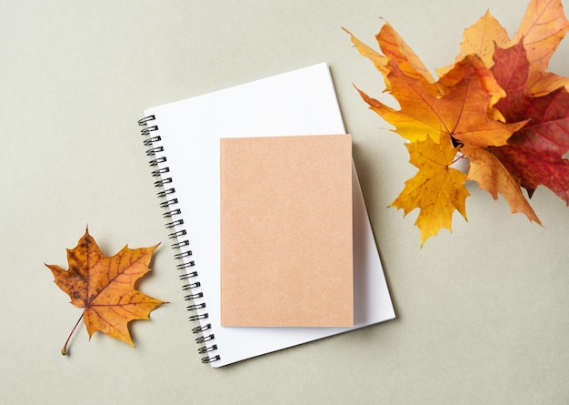 Concept autumn flat lay with yellow maple leaves notebook and notepad on a pastel green background Top view and copy space