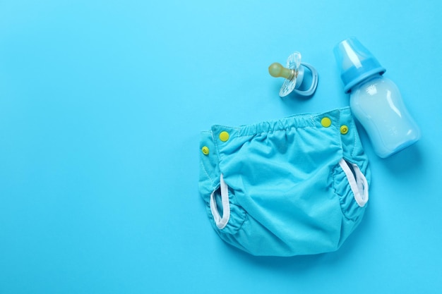 Concept of baby clothes with reusable diapers on blue background