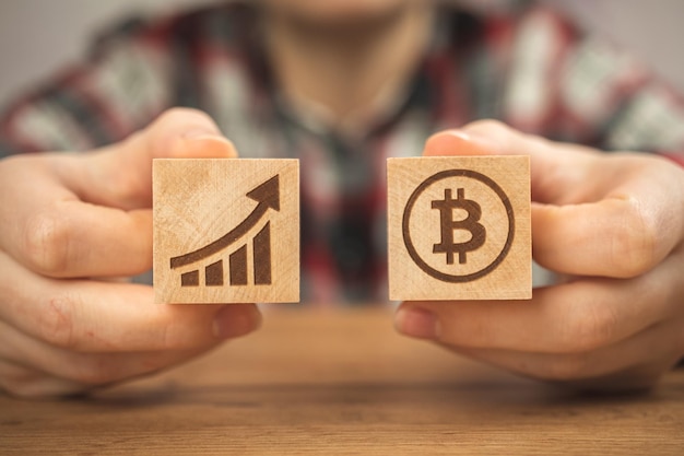 Concept of bitcoin growth BTC graph of the growth symbols on a wooden cubes in hands closeup view photo