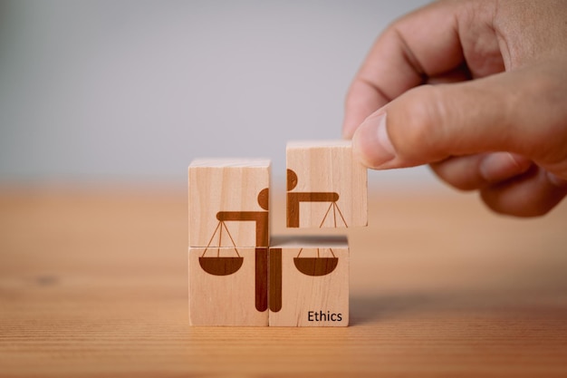 Photo concept of business ethics and moral principles as a hand holds wooden cubes with ethics symbols this emphasizes the importance of business integrity good governance policies and ethical