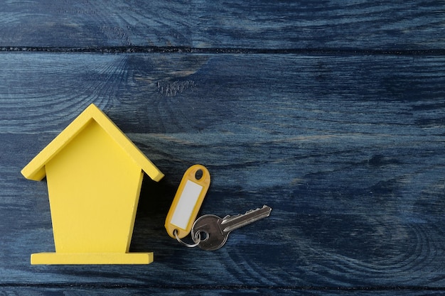 The concept of buying a home Decorative hut and house keys on a blue wooden background with a place for an inscription top view