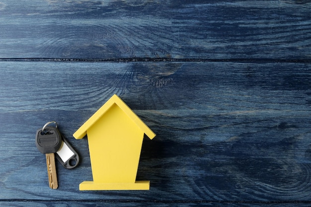 The concept of buying a home Decorative hut and house keys on a blue wooden background with a place for an inscription top view