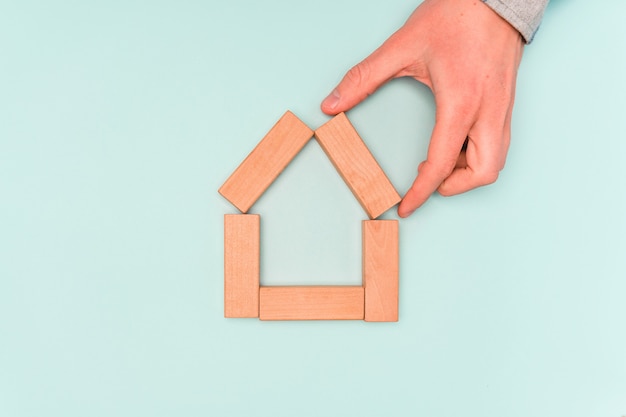 concept of buying a home or renting. hand holds wooden blocks in the form of a house