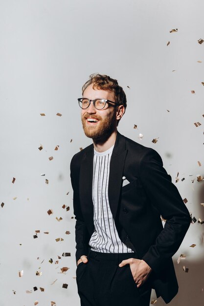 Concept of celebration and victory Stylish young man isolated on white background under glittering confetti