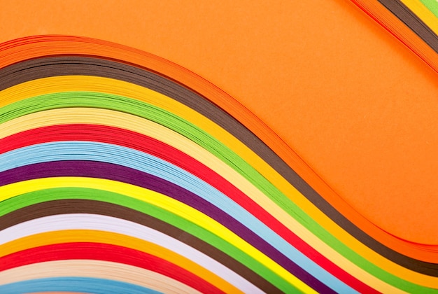 The concept of children's creativity, hobby, recreation curl rainbow strip paper on orange surface