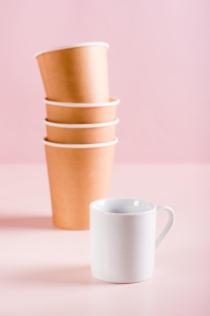 The concept of choosing between a ceramic and paper coffee cup Reusable tableware Vertical view