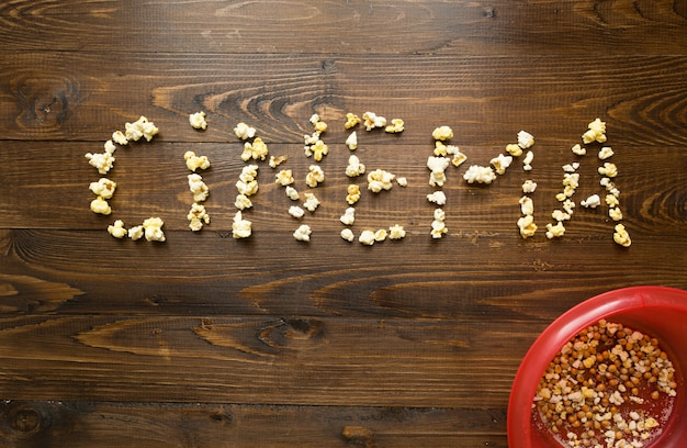 Photo concept of cinema. word cinema spelled with popcorn over wooden background