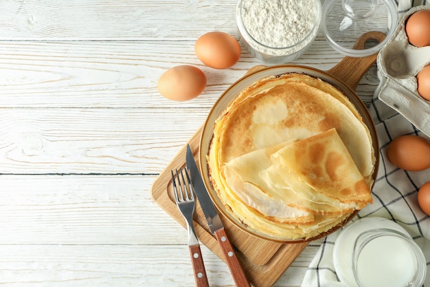 Concept of cooking with crepes on white wooden table