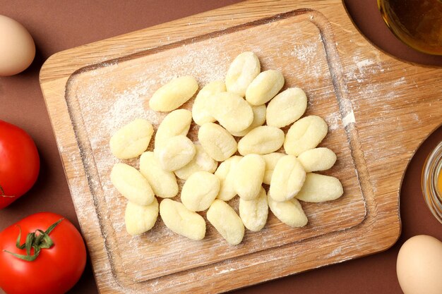 Concept of cooking with potato gnocchi on brown background