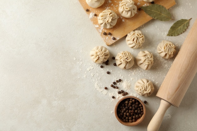 Concept of cooking with raw khinkali and spices on white textured