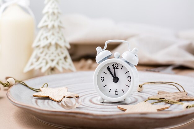 Photo concept countdown on christmas night. table setting. alarm clock five to twelve on a plate and christmas eco decorations on the table