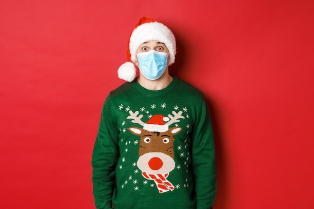 Concept of covid-19 and Christmas holidays with handsome young man wearing a mask