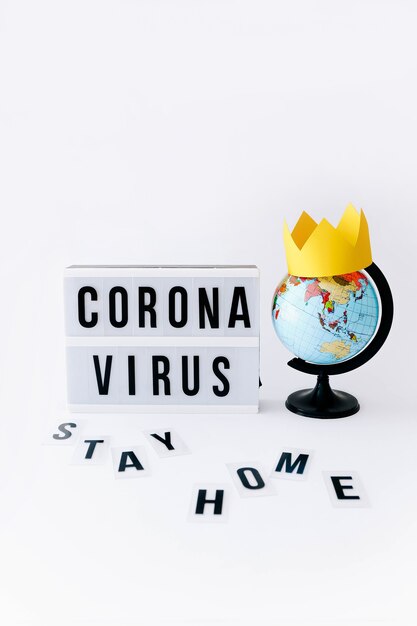 Concept of Covid 19, Corona virus text on display in lightbox and globe with crown on it, light table.