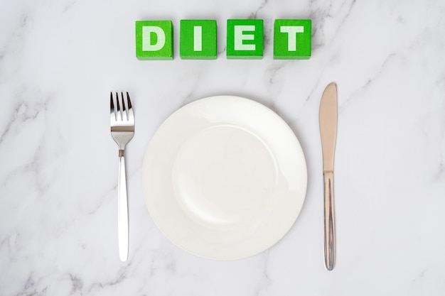 The concept of a diet An empty white plate with a fork and a table knife