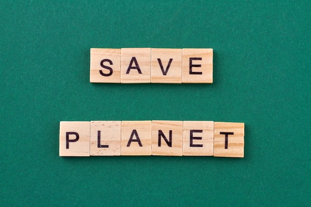 Concept of ecology concern. Text save planet written with wooden cubes isolated on green background.