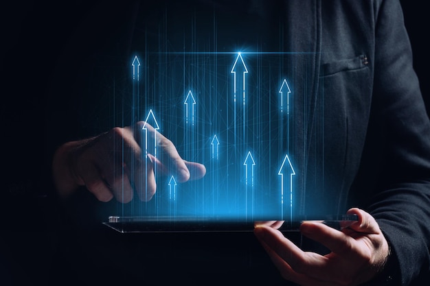 The concept of economic and financial business growth success with up arrows over a tablet in the hands person