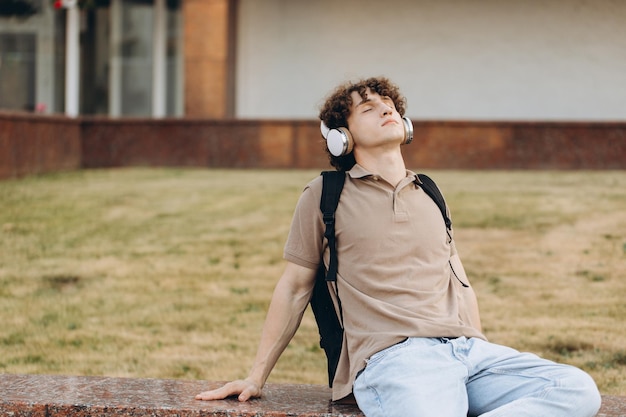 Concept of elearning distance study or remote learning concept Young happy curly hair school guy college or university student with backpack and headphones