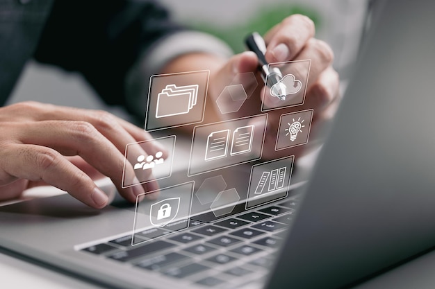 The concept of enterprise resource planning (ERP) and management documentation. A businessman uses a laptop with simulated digital screen icons to do work.