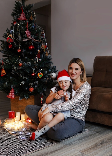 Concept of family, Christmas, holidays and people-happy mother and little daughter sitting at home on the couch