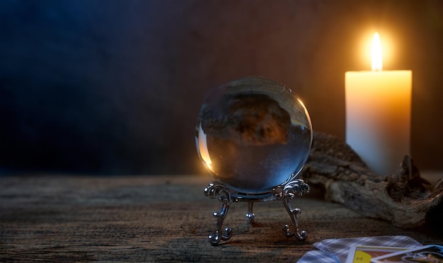 concept of fortune-telling wooden table and white candle with a crystal ball and tarot cards