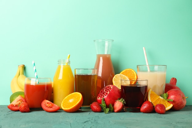 Concept of glasses and bottles with different juices on green