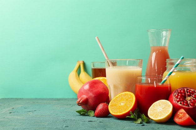 Concept of glasses and bottles with different juices on green