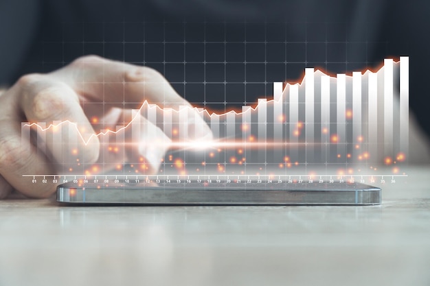 The concept of growth of various indicators in business The person points to the hologram of the growth chart above the smartphone