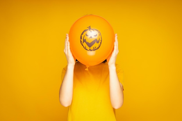 Concept of Halloween Woman holds Halloween balloon on yellow background