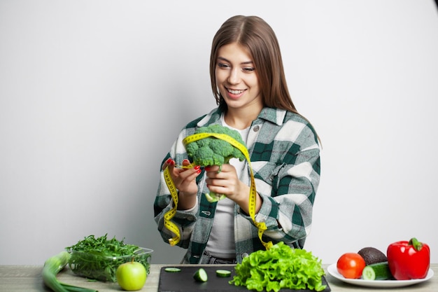 The concept of healthy eating and diet girl holding vegetables on background white wall.