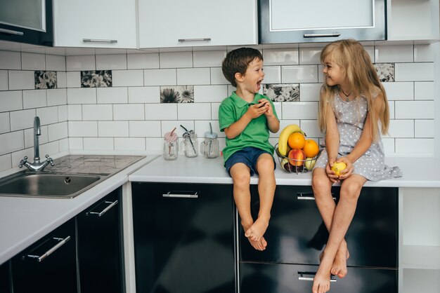 The concept of healthy eating. funny childs with fruits in the kitchen