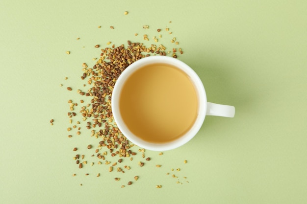 Concept of hot drink with buckwheat tea on green background