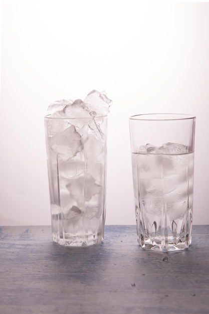 The concept of ice melting One glass full of ice the other half full of water Vertical orientation