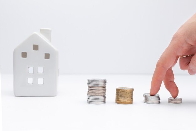 Concept of investment in property hand putting coin with a white house on background