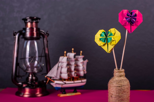 Concept of love handmade papercraft origami crafted colored paper heart close-up shot in studio with lamp and boat