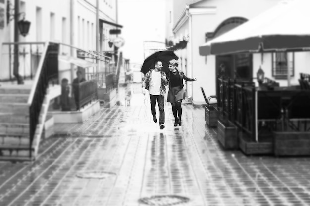 Concept of love loving couple under an umbrella walking down the street of the cityblackandwhite pho