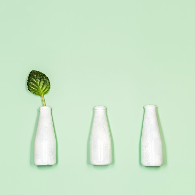 Concept of natural cosmetic with bottles and leaf on light green background