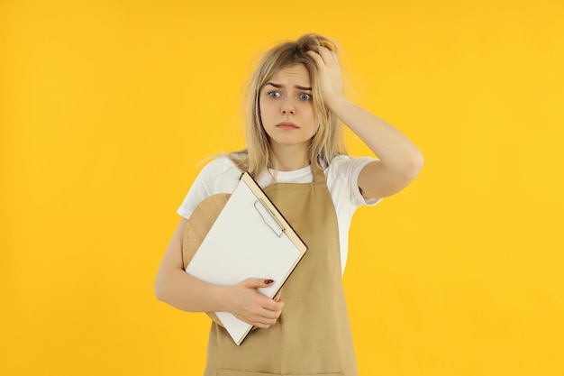 Concept of occupation young female waiter on yellow background