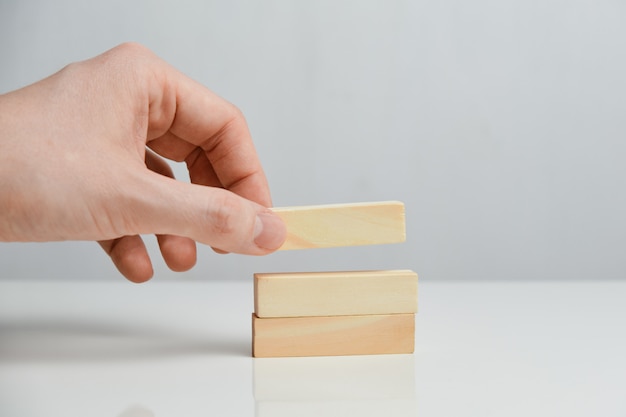 The concept of phased planning. Hand holds wooden blocks on a white space.