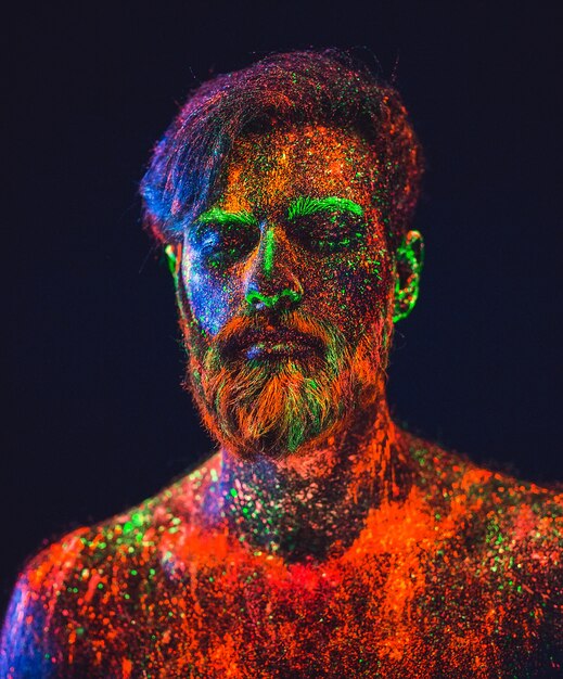 Concept. Portrait of a bearded man. The man is painted in ultraviolet powder.