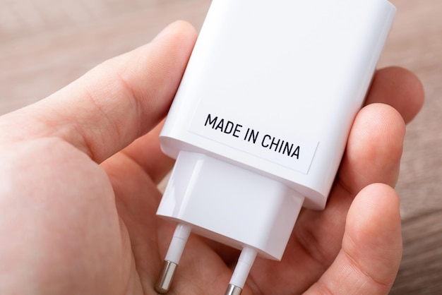 Concept of producing electronics in China Man holding phone charger with inscription Made in China